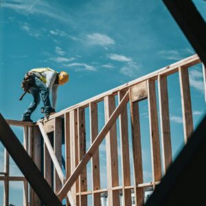 Seorang pekerja sedang berdiri di sebuah fasad bangunan dalam artikel cek IMB dan PBG di website Ecotown.id