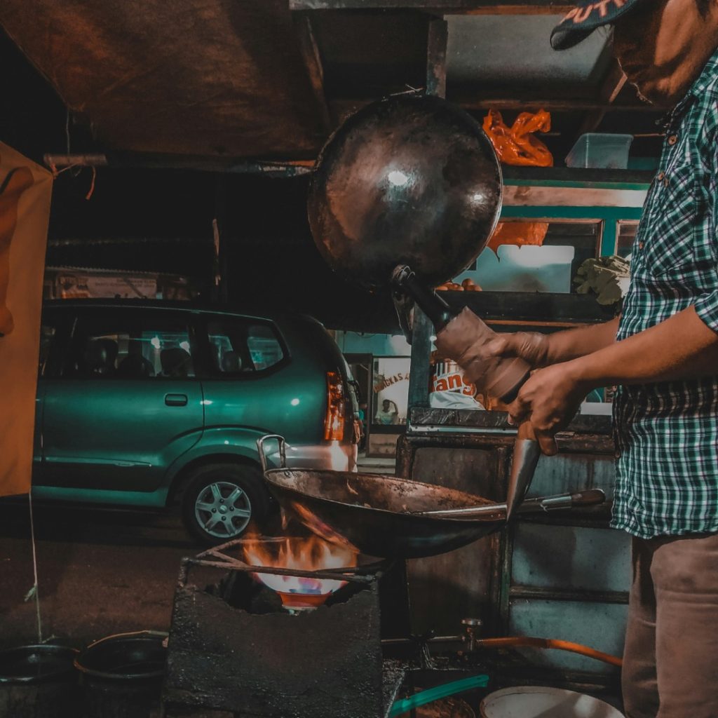 Penjual nasi goreng sedang memasak pesanan dalam artikel tempat nongkrong malam di Depok di website ecotown.id