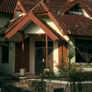 Rumah bergaya klasik dengan atap genteng cokelat, teras depan berkanopi, dan pagar besi di depannya. Gambar ini berada dalam artikel "KPR Rumah Depok" di website Ecotown.id