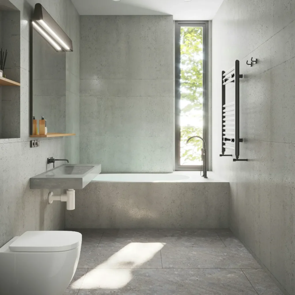 Desain interior kamar mandi minimalis modern bernuansa semen abu-abu dilengkapi wastafel gantung, bathtub, dan pencahayaan alami dari jendela. Gambar ini berada dalam artikel "Renovasi Kamar Mandi Minimalis" di website Ecotown.id